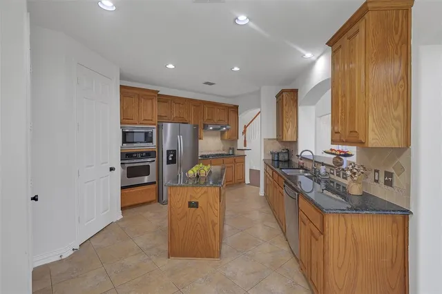 a large kitchen with stainless steel appliances a large counter top a stove and a refrigerator