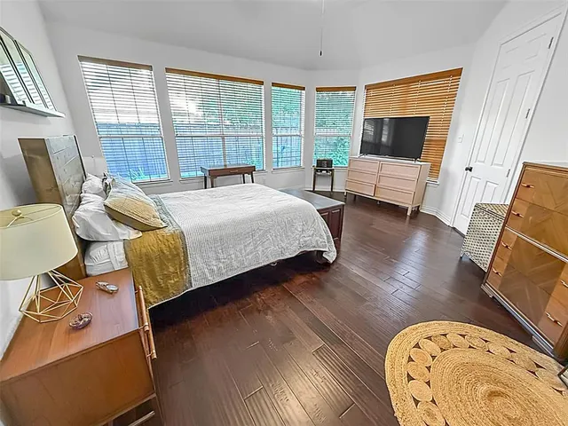 a spacious bedroom with a bed and wooden floor