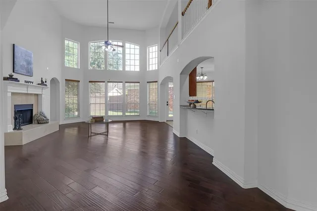 an empty room with wooden floor fireplace and windows