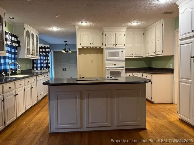 a kitchen with stainless steel appliances granite countertop a stove a sink dishwasher and a refrigerator with wooden floor