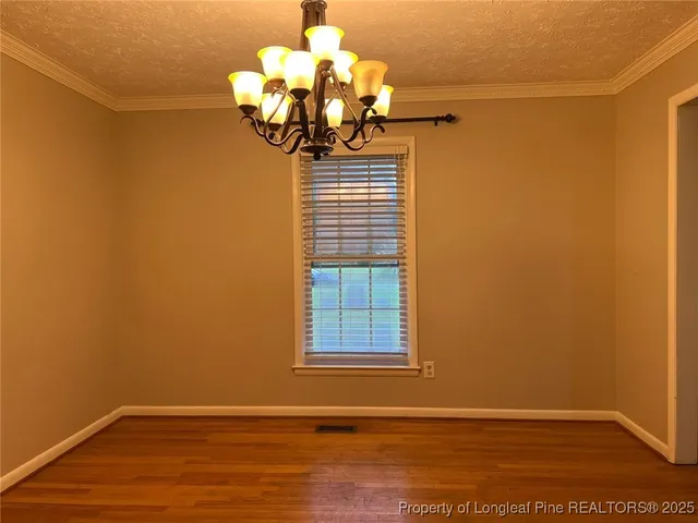 a view of a room with wooden floor and chandelier