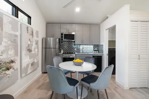 a kitchen with stainless steel appliances a dining table chairs and refrigerator