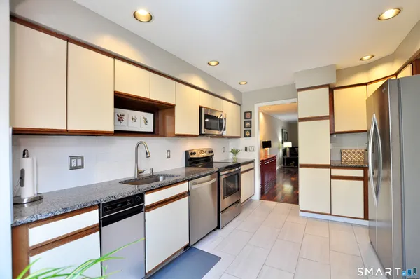 a kitchen with stainless steel appliances granite countertop a refrigerator a stove top oven a sink and dishwasher