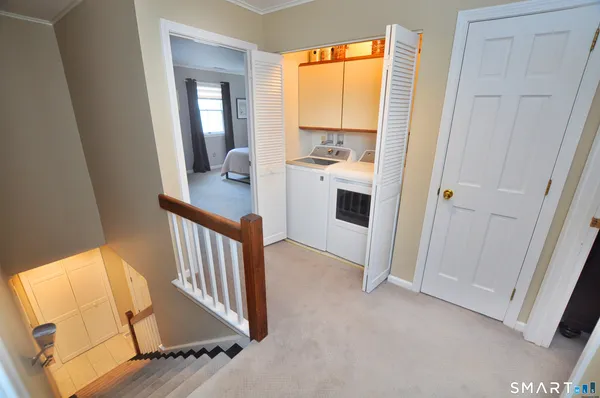 a view of a hallway with wooden floor and a bathroom