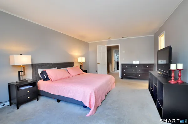 a spacious bedroom with a bed and a flat screen television