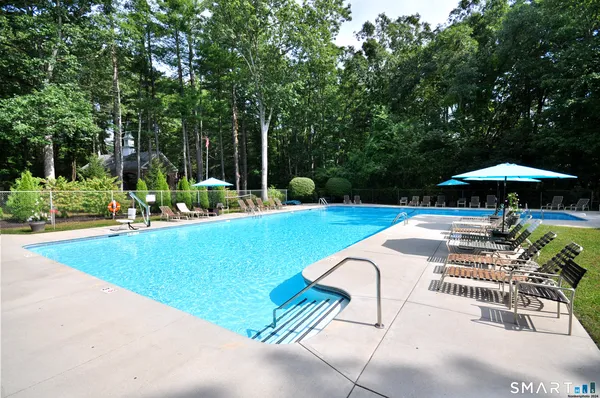 a view of pool with lawn chairs under an umbrella