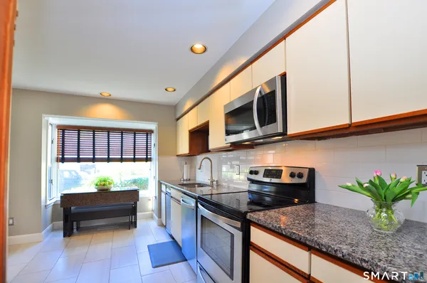 a kitchen with stainless steel appliances granite countertop a stove a sink and a microwave