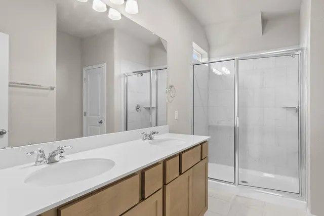 a bathroom with a double vanity sink mirror and shower