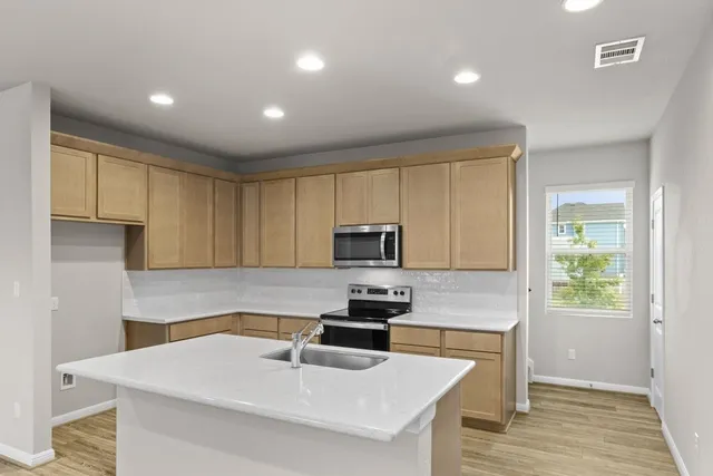 a kitchen with granite countertop a sink stove and microwave