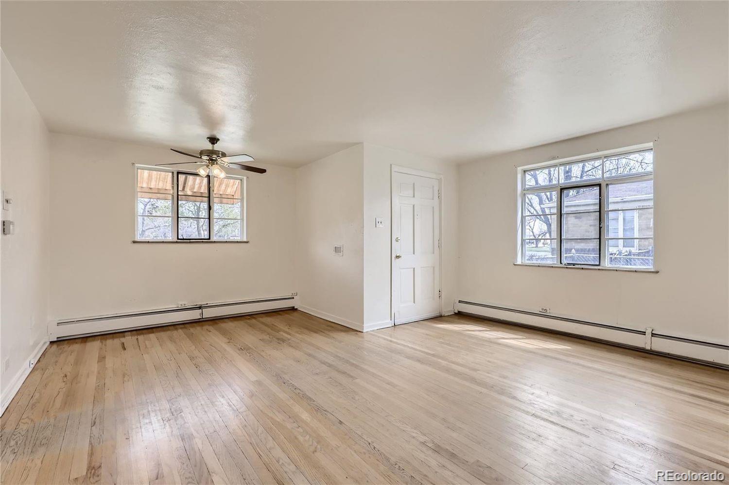 411 Quebec Street Denver, CO 80220 - Photo 4 of 31 an empty room with wooden floor chandelier and windows