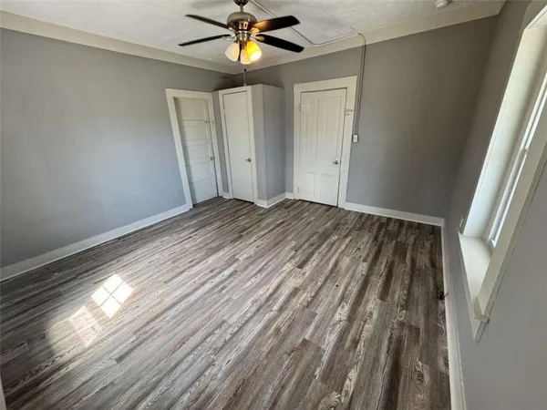 a view of empty room with wooden floor and fan