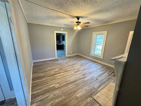 a view of an empty room with a window and wooden floor