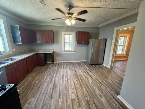 a kitchen with stainless steel appliances granite countertop a refrigerator a sink dishwasher a stove and white countertops with wooden floor