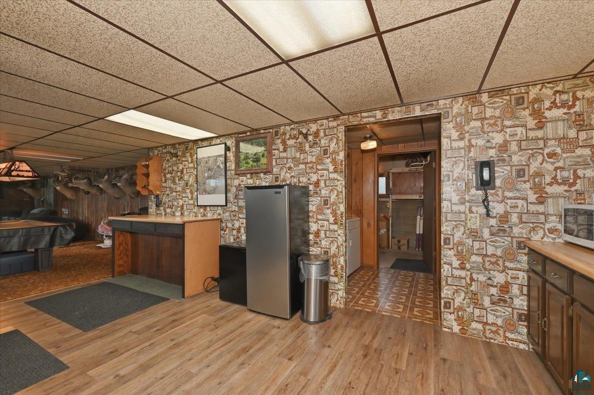 5190 County Road M Gordon, WI 54838 - Photo 10 of 31 Wood-finish flooring throughout the main area with patterned wallpaper and a drop ceiling