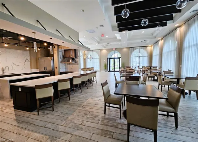 a dining hall with stainless steel appliances kitchen island granite countertop a table chairs and a view of living room