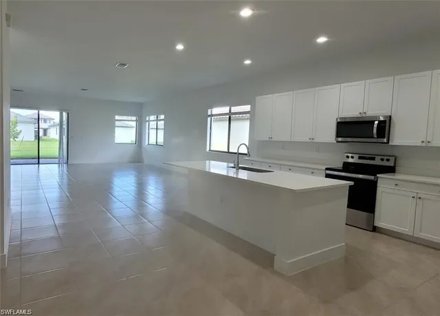 a kitchen with granite countertop a stove a sink and a refrigerator