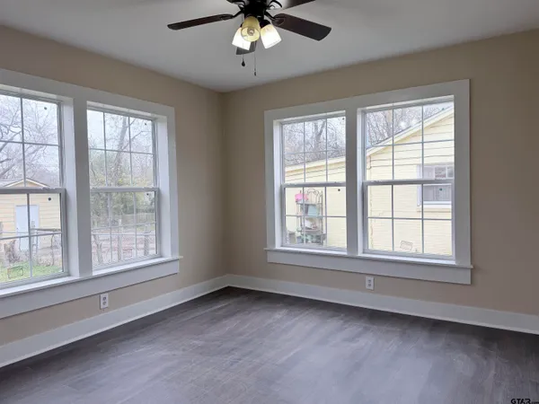an empty room with chandelier fan and windows