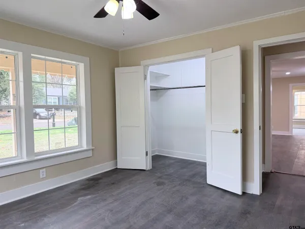 an empty room with chandelier fan and windows