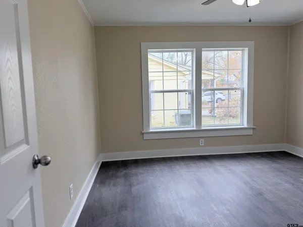 an empty room with wooden floor and windows