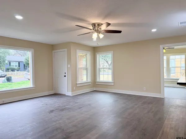 a view of an empty room with a window and wooden floor