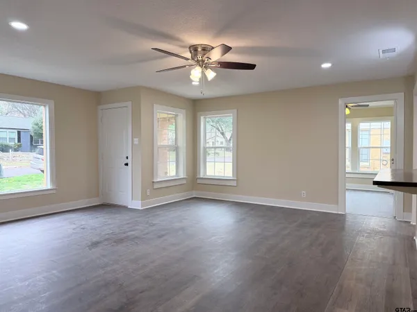 a view of an empty room with wooden floor and a window