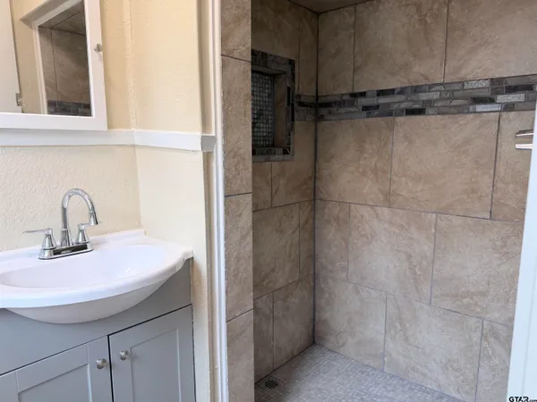 a bathroom with a granite countertop shower and a sink