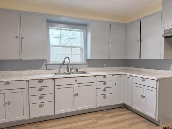 a white kitchen with granite countertop a sink window and cabinets