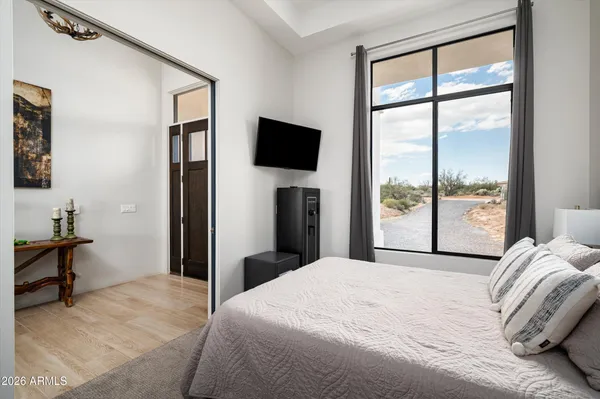 a bedroom with a bed and a flat tv screen next to a window