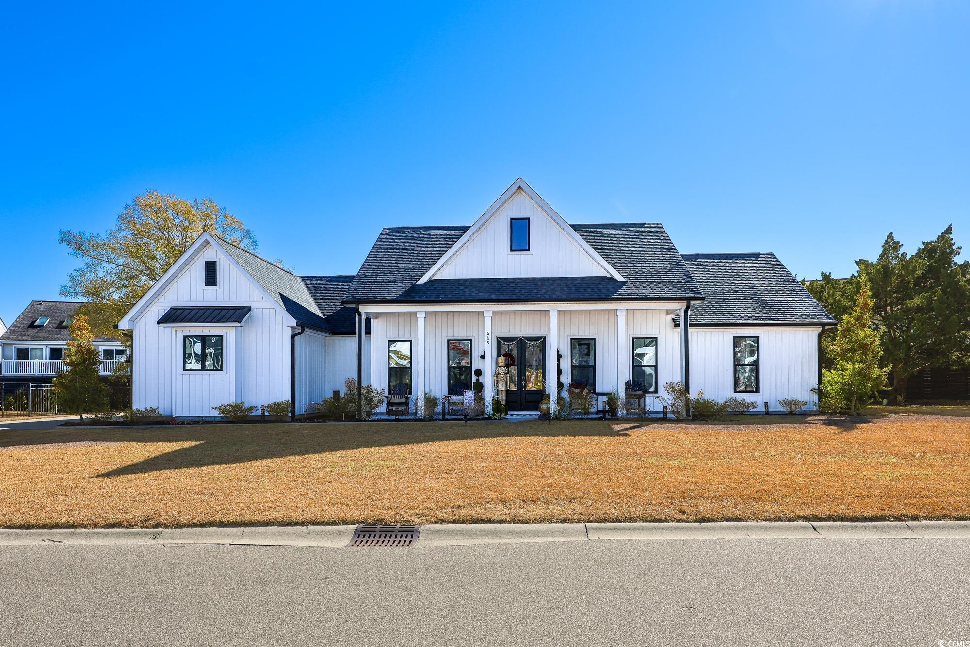 Modern farmhouse style home with a porch, a shingled roof, and a front lawn