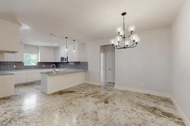 a large kitchen with kitchen island a chandelier stainless steel appliances cabinets and a counter top space