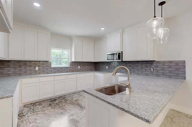 a kitchen with granite countertop a sink a stove and cabinets