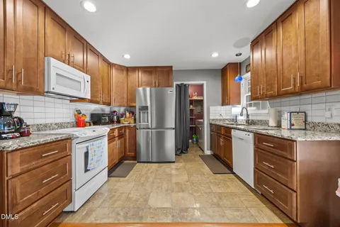 a kitchen with stainless steel appliances granite countertop a refrigerator sink and stove