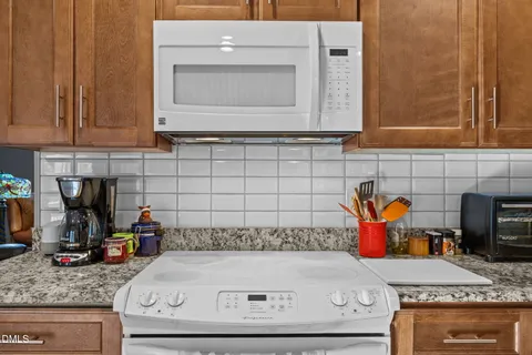 a kitchen with granite countertop stainless steel appliances a refrigerator stove top oven and sink