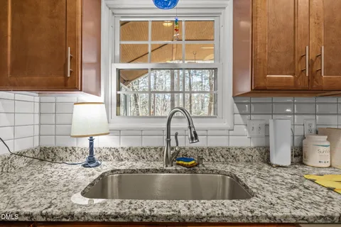 a kitchen with granite countertop a sink and a stove with white cabinets