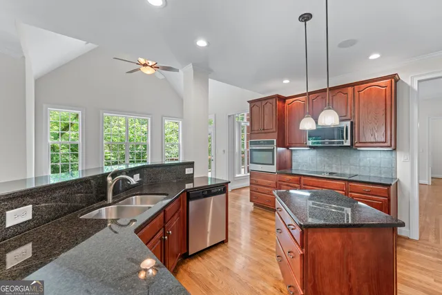 a kitchen with stainless steel appliances granite countertop a sink a stove and a wooden floor