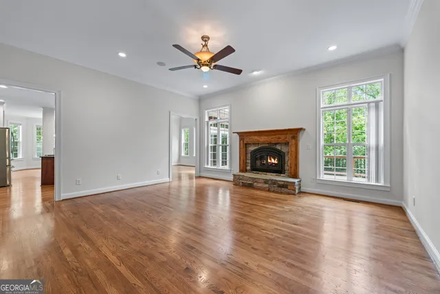 a view of an empty room with wooden floor fireplace and a window