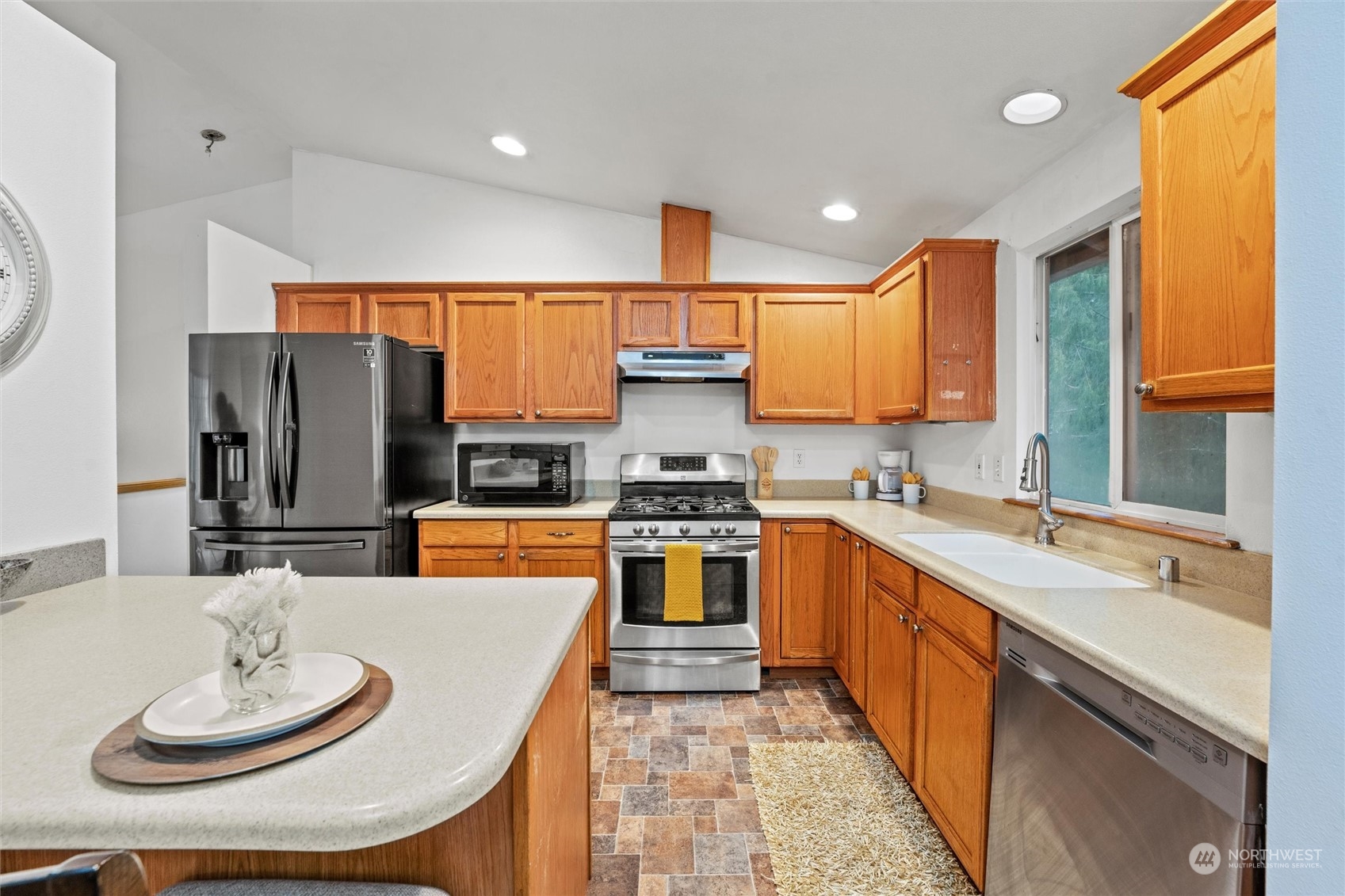 4574 Knute Anderson Road Northwest Silverdale, WA 98383 - Photo 28 of 39 a kitchen with stainless steel appliances a sink a stove a refrigerator and a dining table with wooden floor