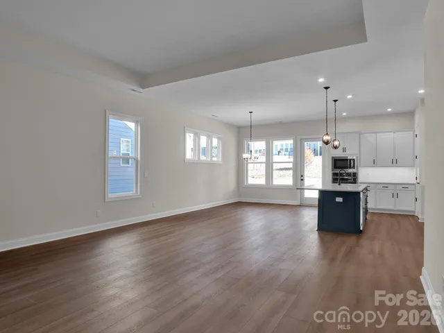 a kitchen with stainless steel appliances granite countertop a stove a sink a refrigerator and a wooden floor