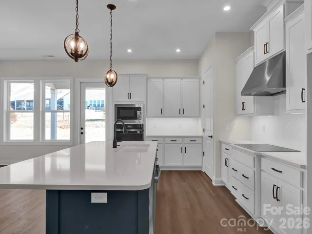 a kitchen with stainless steel appliances kitchen island granite countertop a sink a stove and cabinets