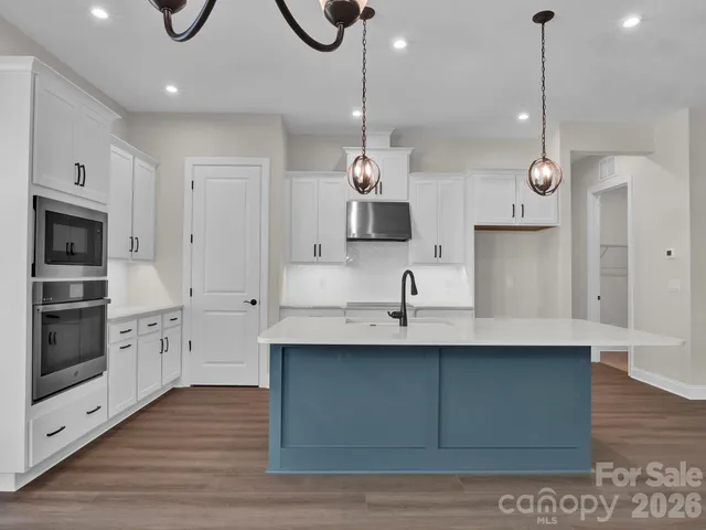 a kitchen with stainless steel appliances granite countertop a sink a stove and a wooden floors