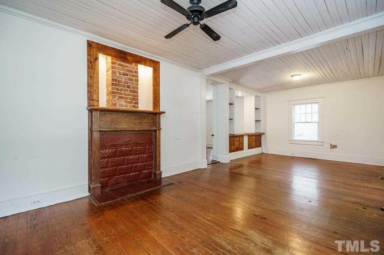105 East Whitaker Mill Road Raleigh, NC 27608 - Photo 5 of 21 an empty room with wooden floor a ceiling fan and windows