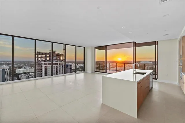 a large white kitchen with kitchen island a large counter top space and stainless steel appliances
