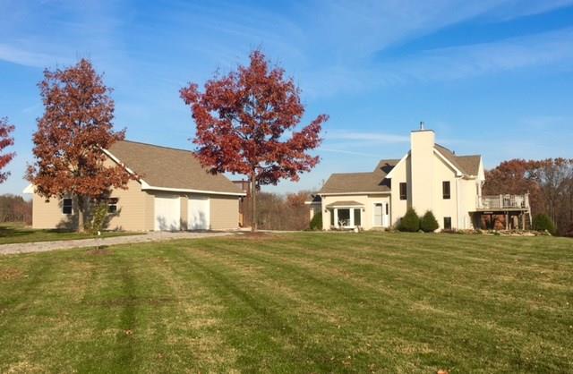 Impressive curb appeal as you come in closer from the street with mature landscaping, grape vines, and tree line of the countryside in the distance.
