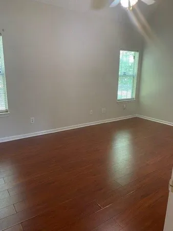 an empty room with wooden floor and windows