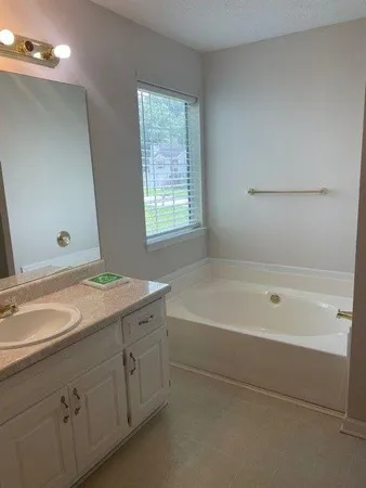 a spacious bathroom with a tub sink and mirror