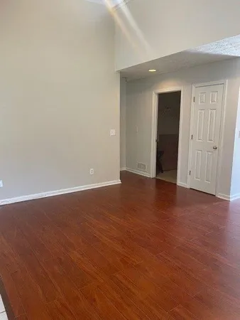 a view of an empty room with wooden floor and closet