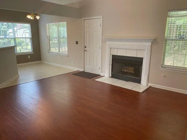 an empty room with wooden floor fireplace and windows