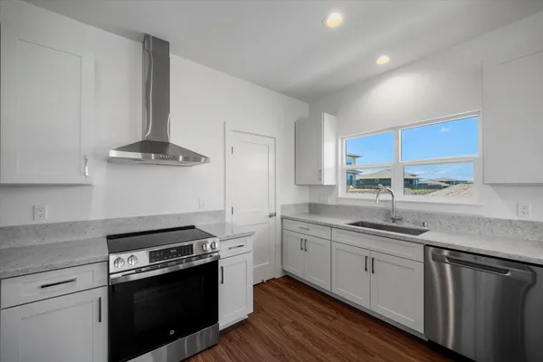 a kitchen with stainless steel appliances a refrigerator a stove and white cabinets