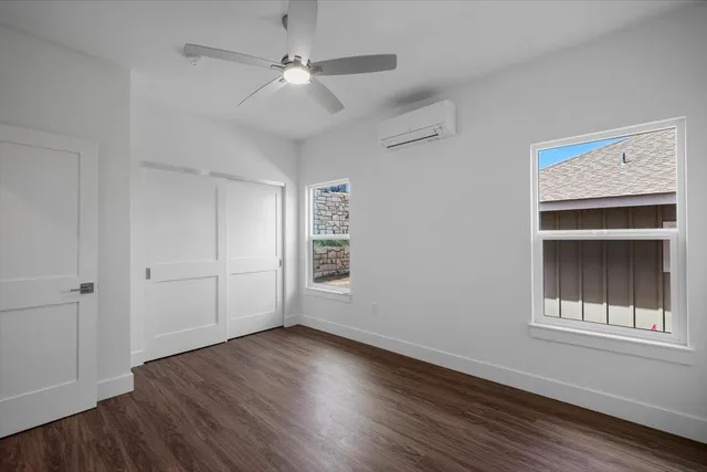a view of an empty room with a window and wooden floor