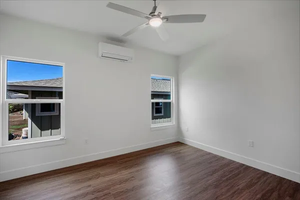 an empty room with wooden floor chandelier fan and windows